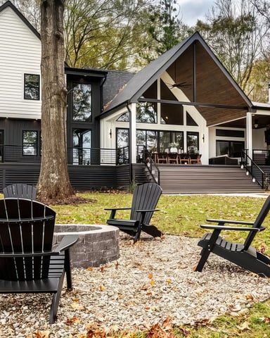 Modern farmhouse with black and white exterior, large deck, and fire pit surrounded by Adirondack chairs in wooded setting.