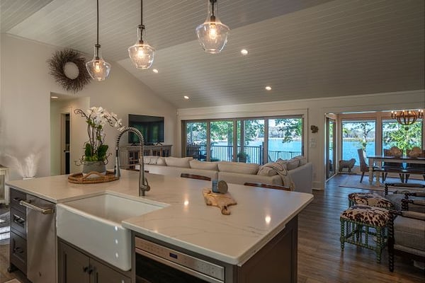 Modern kitchen with white quartz island, pendant lights, and waterfront views through large windows