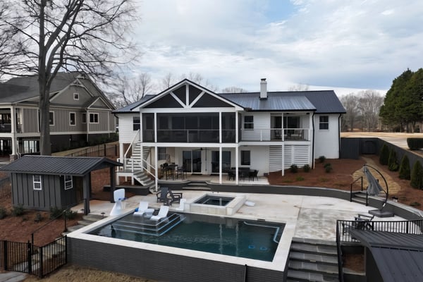 Modern white farmhouse with screened porch, pool, hot tub, and fire pit on expansive patio